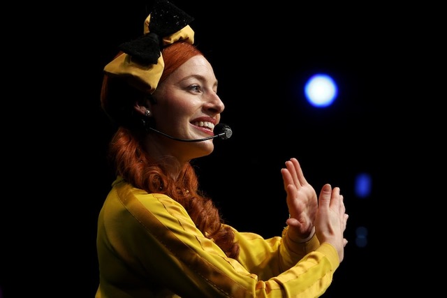 Performer wearing yellow uses sign language to the crowd.
